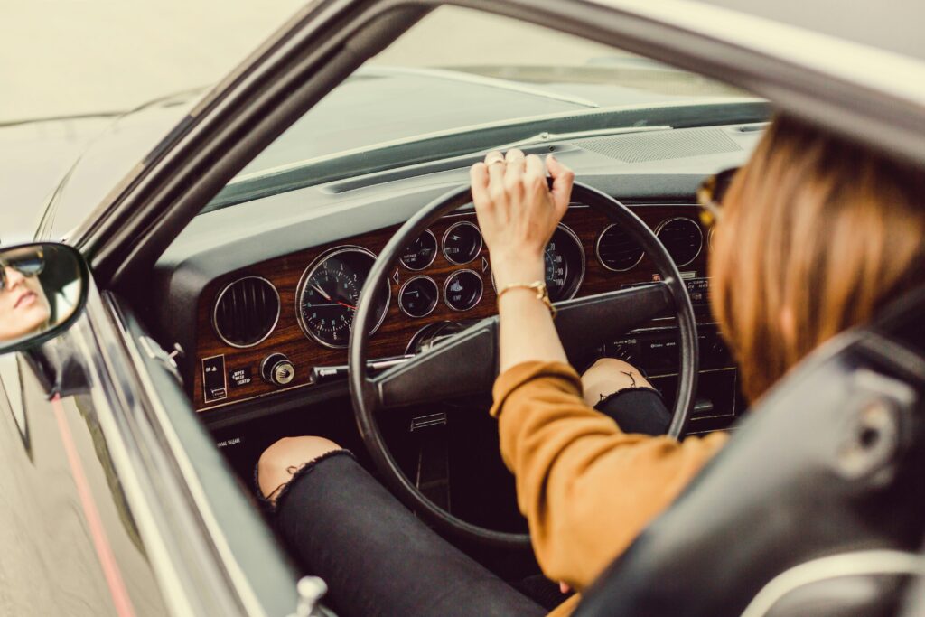 Woman driving a classic car with luxury interior, showcasing style and elegance.